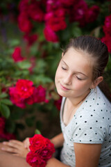 Cute girl in blossoming rose garden