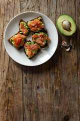 Homemade toast on brown dark wooden rustic background. Open sandwich with dark rye bread, avocado and salmon. top view, free space. Healthy protein food, breakfast, lunch concept. Gourmet snack