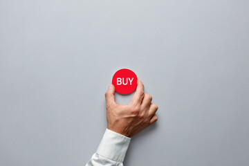 Businessman hand holding a red badge with the word buy. Buying decision in finance or real estate