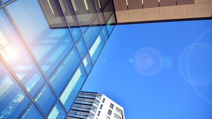 A residential building and an adjacent office building. Modern urban development. Buildings against blue sky and sun light.