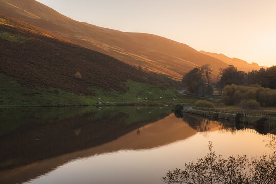 A calm, still peaceful countryside landscape at sunset or sunrise at Glencorse Resevoir in the Pentland Hills Regional Park in Edinburgh, Midlothian, Scotland.