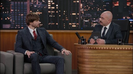 Late-night talk show host having a funny conversation with celebrity male guest in a studio. TV broadcast style show