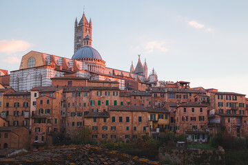 Scenic sunset or sunrise rooftop village view of Duomo di Siena and old town of Siena, Italy in the heart of Tuscany.