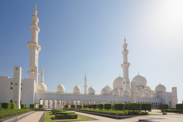 Fototapeta na wymiar Exterior view of Sheikh Zayed Grand Mosque in Abu Dhabi, UAE from the gardens with no people on a clear sunny day.