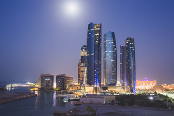 Fototapeta na wymiar A unique and different perspective of skyscraper towers and cityscape skyline of Abu Dhabi, UAE at night under moonlight.