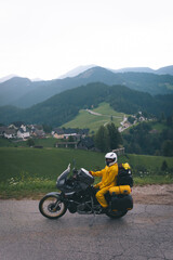 A girl in a yellow raincoat, shoe covers and a motorbike helmet. Motorcyclism and travel. Vertical...