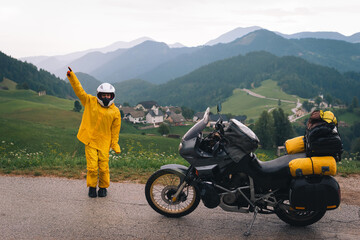 A happy girl in a yellow raincoat, shoe covers and a motorbike helmet. Motorcyclism and travel. Top...