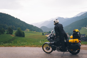A motorcycle driver with motorbike, Adventure vacation, biker dressed in raincoat. sealed bag,...