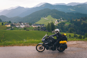 A motorcycle driver with motorbike ride, Adventure vacation, biker dressed in raincoat. sealed bag,...
