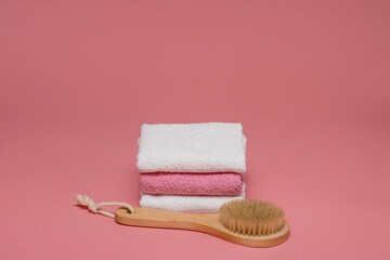 Body brush for anti-cellulite massage and skin treatment with soft towels on pink background. Lay out design with copy space. Spa concept.