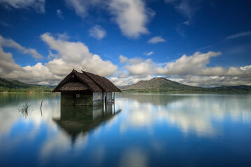 Batur lake, Kintamani, Bali in the morning after sunrise. there is beautiful Batur volcano view with blue sky and perfect reflection in the water.