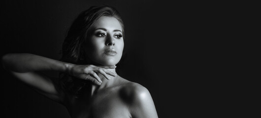 Fototapeta na wymiar Stunning woman with naked shoulders posing in the dark