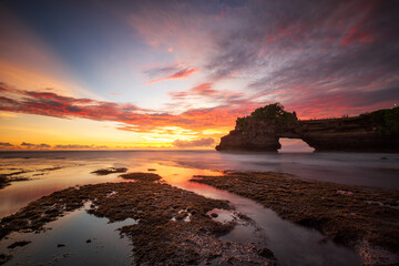 Sunset at Batu Bolong temple and Tanah Lot, Tabanan, Bali. beautiful color with the coral reef in low tide.