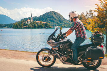Rider man in jeans and a helmet is rides his motorcycle with bags. Tourism and vacation. Sunny...