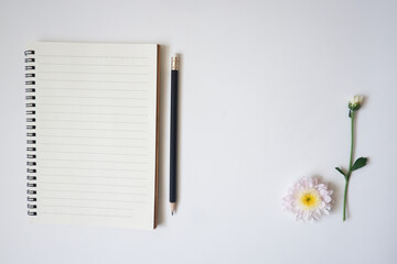 The top view of white background with notebook, white flower and their leaves use for your information or text message.