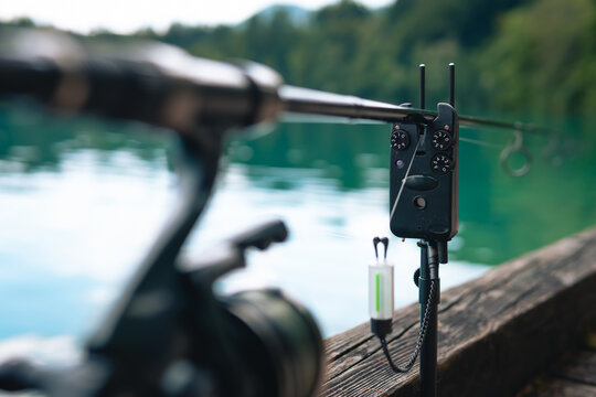 Electronic indicator, bite alarm, Spinning reel on a green blurred background. Concept: outdoor activities, fishing, outdoor recreation. Selective focus.