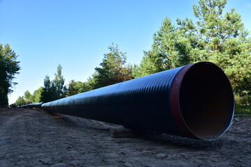 Natural gas pipeline construction work in forest area.  Petrochemical Pipe on top of wooden supports. Installation and Construction the Pipeline for transport gas to LNG plant