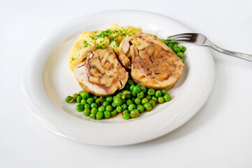 Chicken roulade, stewed pea and mashed potato on white plate.