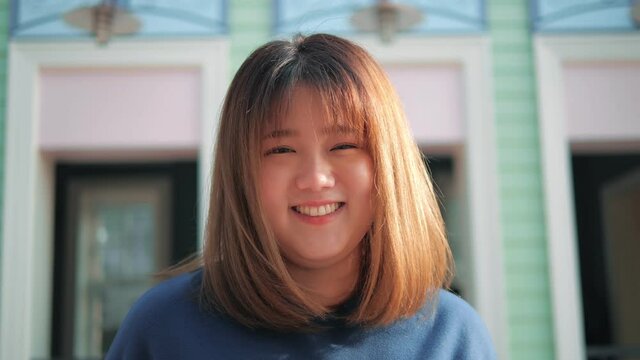Portrait of young pretty asian woman plump smiling and looking at camera outdoors. Front view.