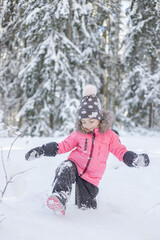 Fototapeta na wymiar Outdoor portrait of little smiling girl, walking in winter forest, have fun and enjoy snow.