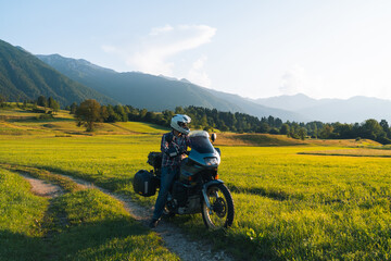 Man motorcyclist ride touring motorcycle. Alpine mountains on background. Biker lifestyle, world traveler. Summer sunny sunset day. Green hills. hermetic packaging bags. Slovenia