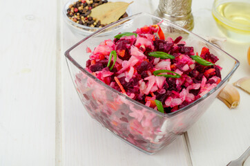 Vegetable salad with beets, spices, onions, garlic on wooden table