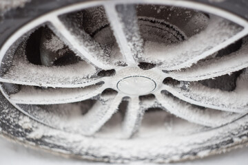 Frost crystals on a wheel. Frozen car with ice. Cold winter day.