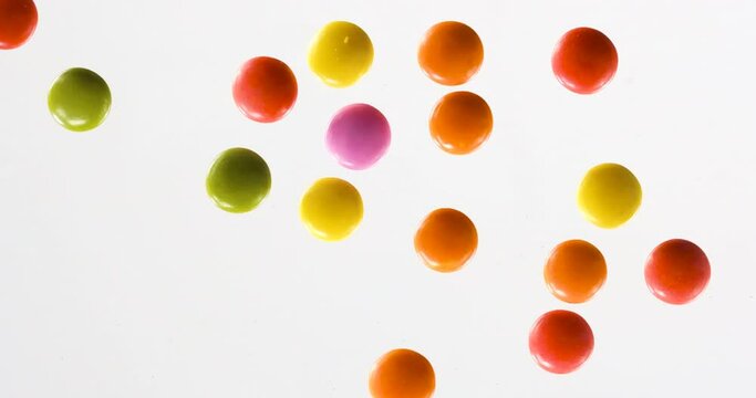 The Colorful dragee chocolates fall from hand to glass. Slow motion. M&M Bonibon. Bonbon.