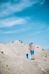 blonde girl in a light blue dress and a guy in a light shirt in a granite quarry