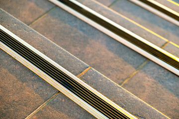 Closeup of ceramic tiles covering porch stairs with rubber anti slippery stripes on it.