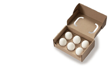 Close-up view of raw chicken eggs in egg box on white wooden background