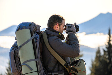 Photographer with hiking backpack taking pictures of nature with digital photo camera.
