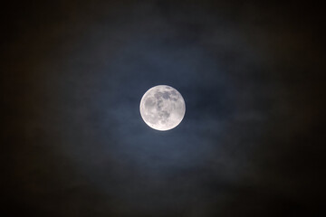 Naklejka na ściany i meble Full bright moon with illuminated clouds in front of it.