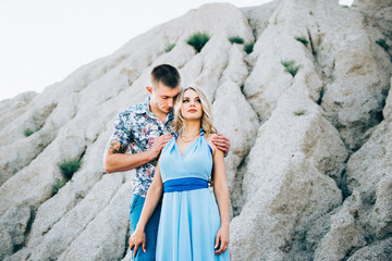 blonde girl in a light blue dress and a guy in a light shirt in a granite quarry