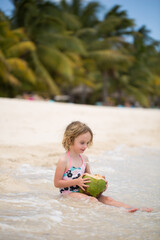 Little preschool kid girl drinking coconut juice on ocean beach.