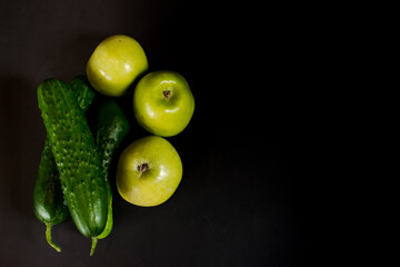 the green fresh bright vegetables and fruit on a black background.