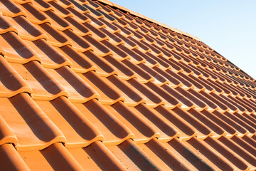 Overlapping rows of yellow ceramic roofing tiles covering residential building roof.