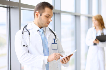 Smiling doctor waiting for his team while standing upright