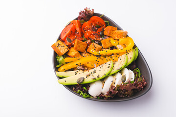 Top view photo of vegetarian fresh salad with pepper avocado tomatoes and tofu.