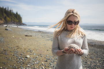 A young woman admires a sea rock on the scenic Mystic Beach located along the shores of the Strait...