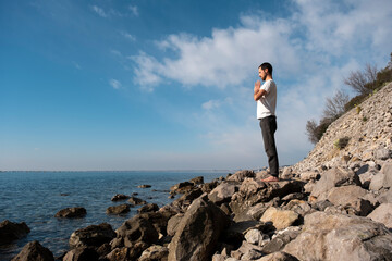 Obraz premium Attractive young man practicing yoga meditation and breathwork outdoors by the sea