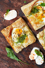 ovos assados com mozzarella em massa folhada, vista de cima em fundo escuro. 