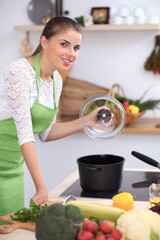 Young woman is cooking soup in the kitchen