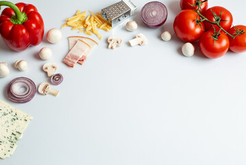 Ingredients for homemade pizza on a white background. Cooking products: tomato, sweet pepper, mushrooms, cheese, onion. Top view with copy space on a white background. Close-up.