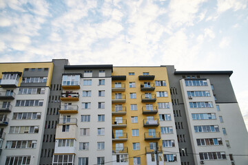 View from underneath on colorful pink apartment building in front of blue sky with clouds. City dwelling. Urban architecture concept.