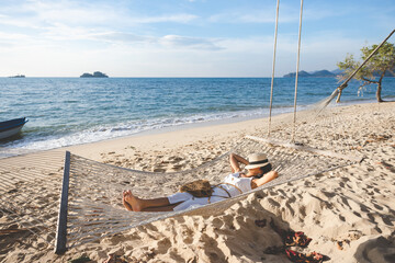 Fototapeta na wymiar Traveler asian woman relax in hammock on summer beach Trad Thailand