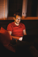Fototapeta premium Portrait of attractive nerdy man is working late night on the computer in living room in home office