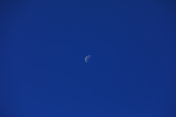 The moon in the blue sky during the day