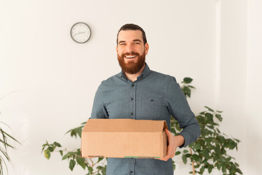 Photo of young smiling man moving to another office or job.