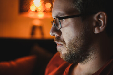 Portrait of attractive nerdy man is working late night on the computer in living room in home office